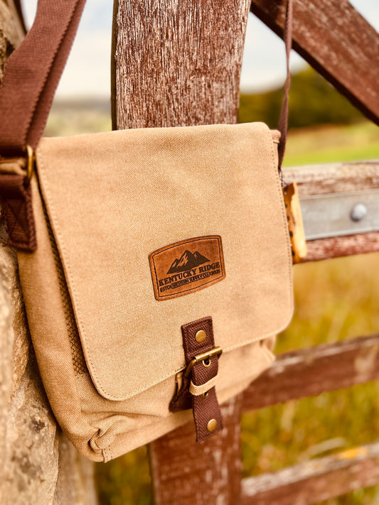 Beige canvas bag with Kentucky Ridge brand logo attached to a wooden fence.
