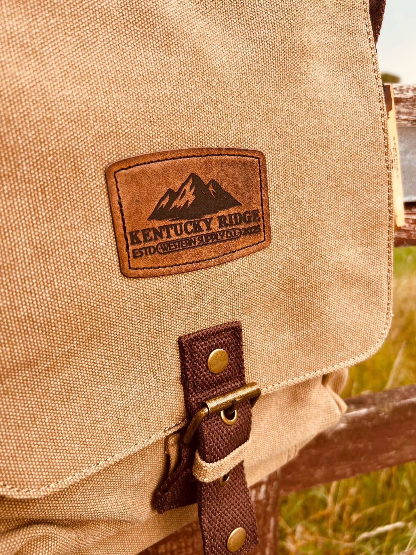 Beige bag with a leather patch featuring the 'Kentucky Ridge' logo, set against a natural background.