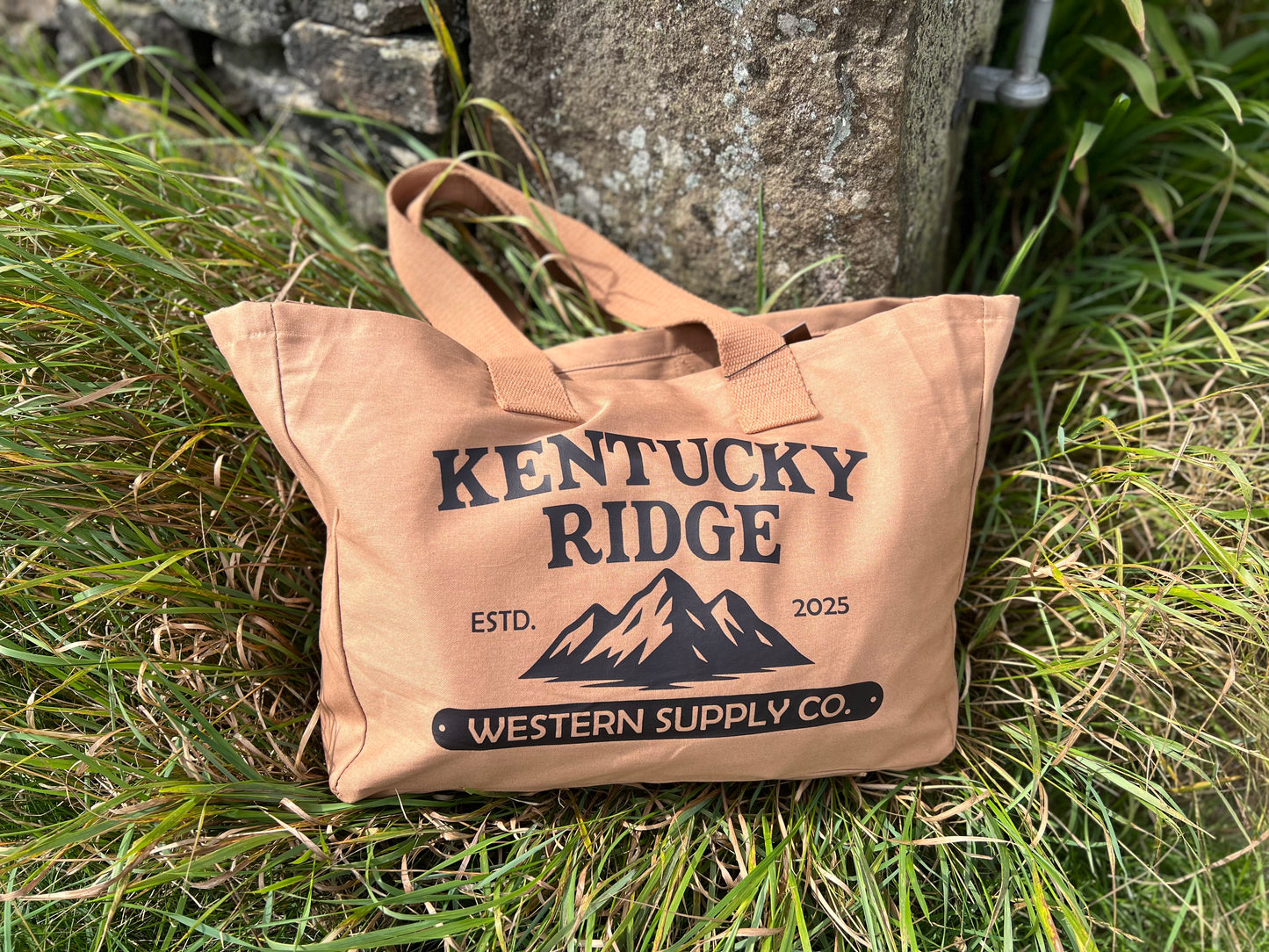 Beige tote bag with 'Kentucky Ridge' branding on grass
