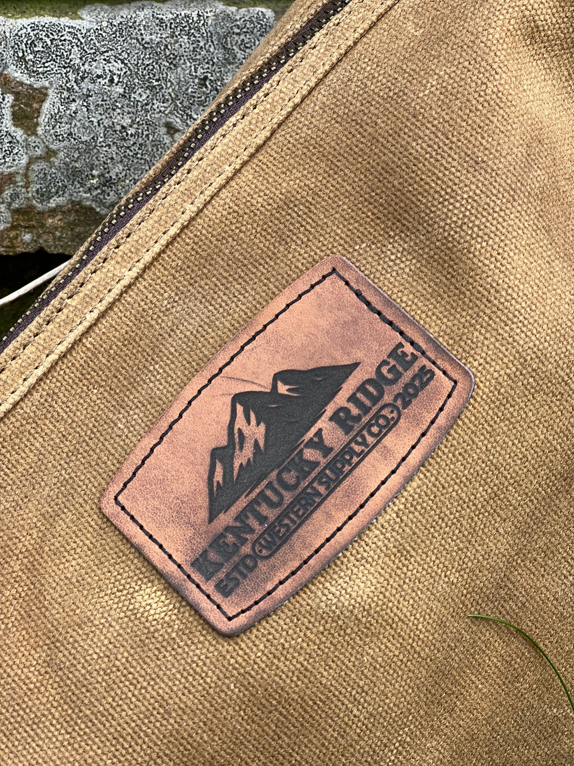 Close-up of a leather patch with 'Kentucky Ridge' branding on a beige fabric background.