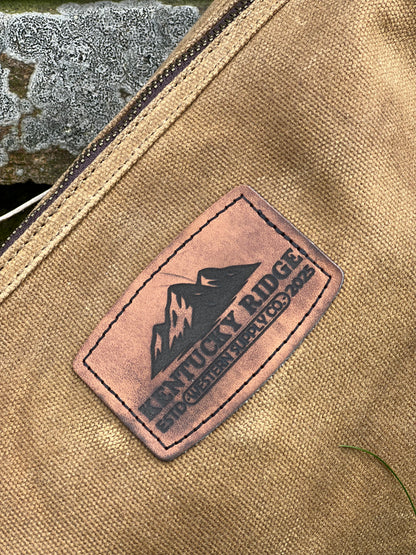 Close-up of a leather patch with 'Kentucky Ridge' branding on a beige fabric background.